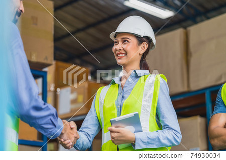 Manager of warehouse worker hand shake with assistant manager woman in local warehouse or factory, Asian and white caucasian people,Partner and colleague working together in success achievement concept Manager of warehouse worker hand shake with assistant manager woman in local warehouse or factory, Asian and white caucasian people,Partner and colleague working together in success achievement concept 74930034