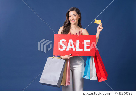 Happy young Asian woman holding sales banner and presenting credit card for online shopping on blue color background, cashless payment, black friday and consumerism concept, carrying shopping bags Happy young Asian woman holding sales banner and presenting credit card for online shopping on blue color background, cashless payment, black friday and consumerism concept, carrying shopping bags 74930085