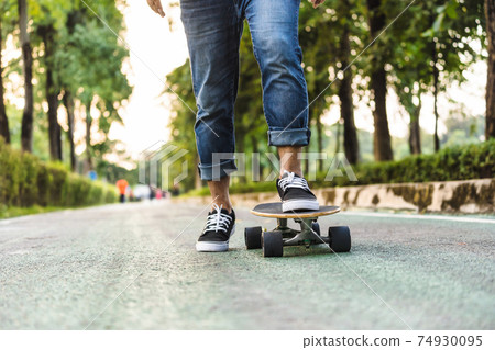 Closeup Asian man leg on surfskate or skate board in outdoor Park when sunrise time over photo blur of unrecognized people running, extream sport, healthy and exercise, fashion in covid19 concept Closeup Asian man leg on surfskate or skate board in outdoor Park when sunrise time over photo blur of unrecognized people running, extream sport, healthy and exercise, fashion in covid19 concept 74930095
