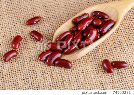 Closeup red beans or kidney bean in wooden bowl isolated on wood table background. Closeup red beans or kidney bean in wooden bowl isolated on wood table background. 74933281