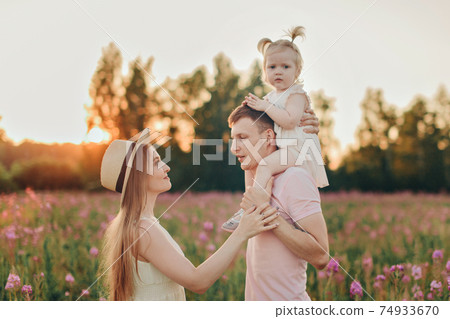 a happy family walks through a flower meadow. Love and spring blooming 74933670