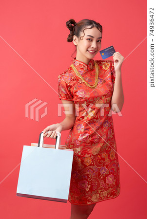beautiful Asian woman wearing traditional cheongsam qipao dress showing credit card, shopping bags beautiful Asian woman wearing traditional cheongsam qipao dress showing credit card, shopping bags 74936472