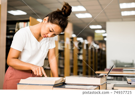 Young Asian women are searching for books and reading from the bookshelves in the college library to research and develop themselves in education Young Asian women are searching for books and reading from the bookshelves in the college library to research and develop themselves in education 74937725