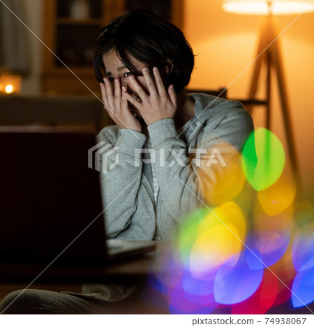 Young woman watching a late-night horror movie Square Young woman watching a late-night horror movie Square 74938067