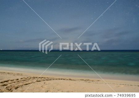 [Yoron Island] Footprints of sea turtles remaining on the sandy beach with twinkling stars and the main island of Okinawa 74939695