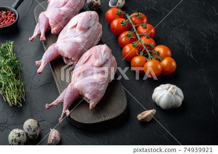Fresh raw meat quails with herbs, on black textured background Fresh raw meat quails with herbs, on black textured background 74939921