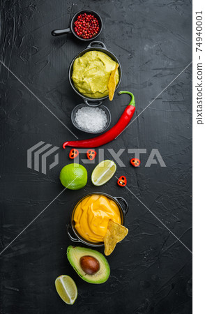 Green guacamole and yellow cheese dip sauce for traditional Mexican tacos, on black background, top view or flat lay with copy space for text 74940001