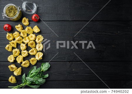 Raw Tortellini with basil and pine pesto, on black wooden table background, top view flat lay, with copy space for text 74940202