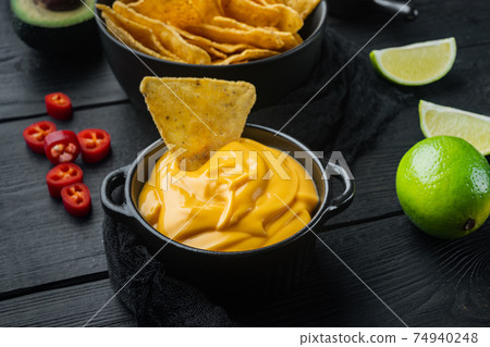 Bowl with cheese sauce, on black wooden background 74940248
