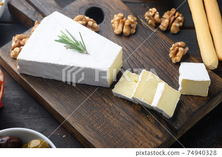 Piece of the brie cheese, on dark wooden background Piece of the brie cheese, on dark wooden background 74940328