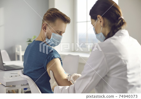 Male patient in medical face mask getting clinical trial vaccine during virus pandemic Male patient in medical face mask getting clinical trial vaccine during virus pandemic 74940373