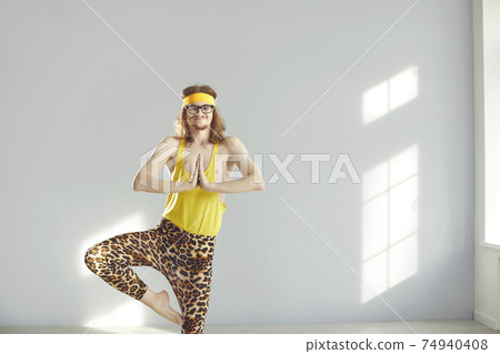 Funny thin long haired male standing in meditation position practicing yoga 74940408