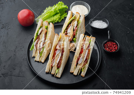 Club sandwich panini with ham, tomato, cheese, on black background Club sandwich panini with ham, tomato, cheese, on black background 74941209