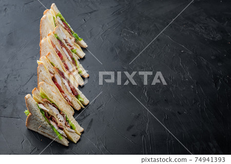 Club sandwich with meat, cheese, tomato, ham, on black background with copy space for text Club sandwich with meat, cheese, tomato, ham, on black background with copy space for text 74941393