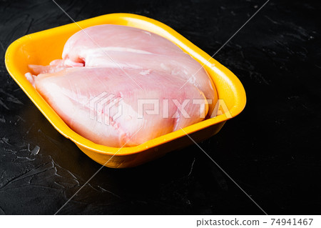 Raw chicken breast fillet in tray, on black background with copy space for text Raw chicken breast fillet in tray, on black background with copy space for text 74941467