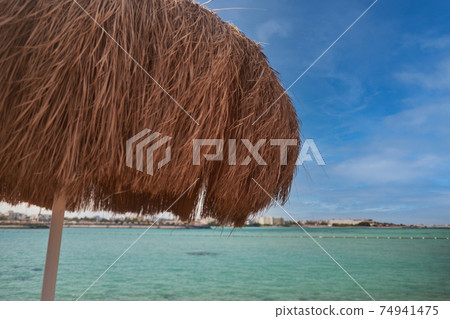 A straw umbrella on a beautiful beach 74941475