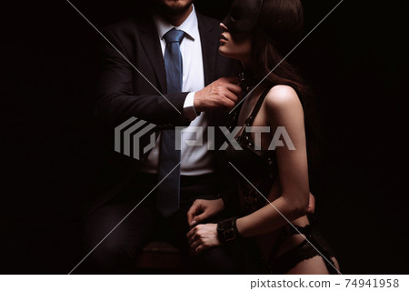 male dominant dominates submissive sexy girl in mask and handcuffs 74941958