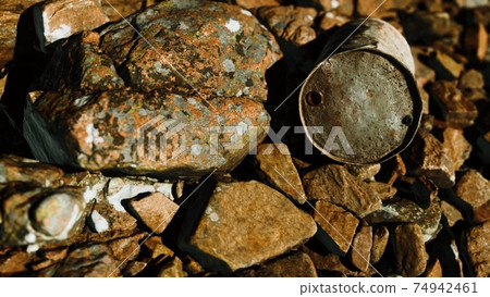 rusty destroyed metal barrel on beach rocks 74942461