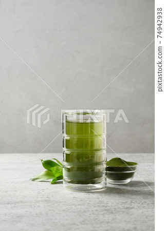 Chlorella healthy beverage in glass on a grey background. 74942938