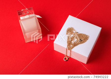 Valentine's Day. Perfume and a box with a chain on a red background.. 74943222