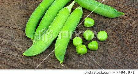 View of fresh ripe green peas lying on a rustic table. Peas in a pod close-up. View of fresh ripe green peas lying on a rustic table. Peas in a pod close-up. 74943971