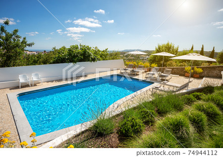 Outdoors shot of a clean pool with some loungers on the side on a clear sunny day. Outdoors shot of a clean pool with some loungers on the side on a clear sunny day. 74944112