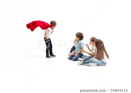 Child pretending to be a superhero with his friends sitting around Child pretending to be a superhero with his friends sitting around 74944115
