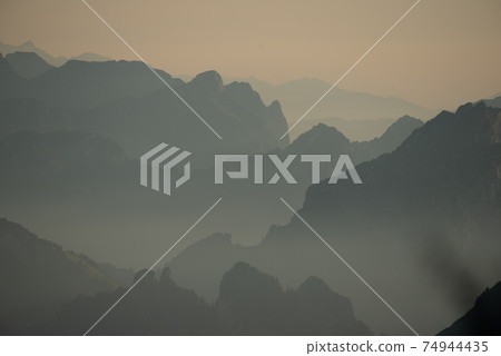 Misty sunset with beautiful silhouette of mountain range in Switzerland Misty sunset with beautiful silhouette of mountain range in Switzerland 74944435