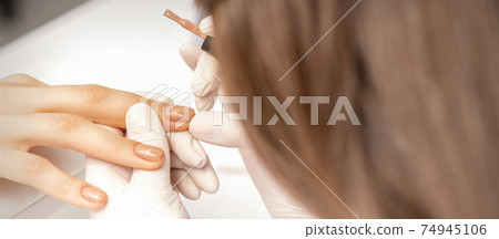 Manicurist applying beige nail polish 74945106