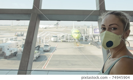 Woman caucasian at airport with wearing protective medical mask on head against the background of the plane. Coronavirus sars-cov-2 covid-19. 74945904