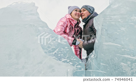 Couple has fun during winter walk against background of ice of f Couple has fun during winter walk against background of ice of f 74946041