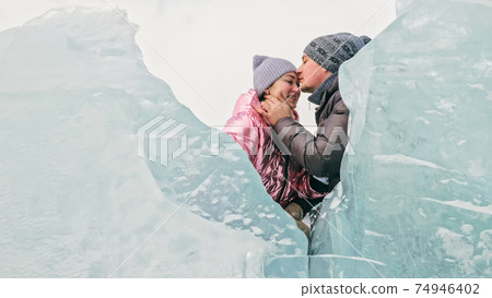 Couple has fun during winter walk against background of ice of f Couple has fun during winter walk against background of ice of f 74946402