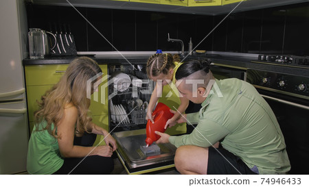 Mother and father teaching daughter learning to use dishwasher. Mistress girl children loading putting dirty dishes in automatic dishwasher. 74946433