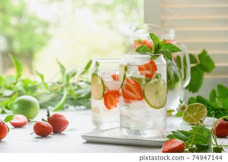 Homemade lemonade with soda, strawberries, and lim. 74947144