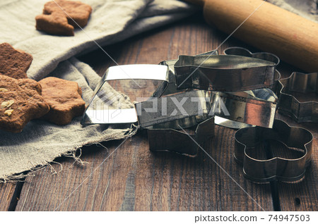 metal cookie cutters and wooden rolling pin on a wooden background 74947503