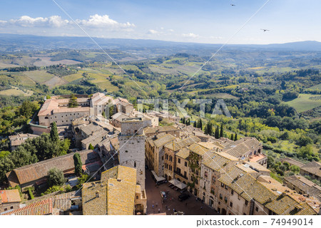 Medieval houses, square and towers of San Gimignano, Italy, and fields, forests and mountains around 74949014