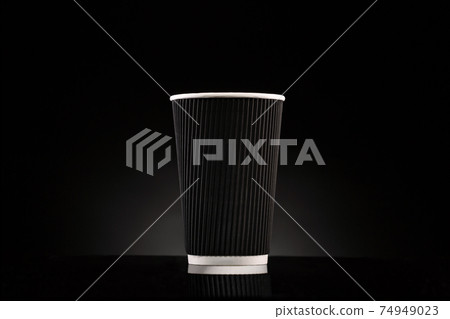Disposable cardboard corrugated cup on a black background. 74949023