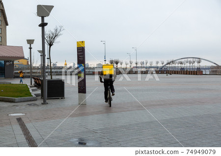 Kyiv, Ukraine - March, 22, 2020: Glovo delivery service courier on an empty Postal Square in Kiev. Kyiv, Ukraine - March, 22, 2020: Glovo delivery service courier on an empty Postal Square in Kiev. 74949079
