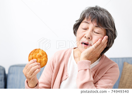 Senior woman eating rice crackers 74949340