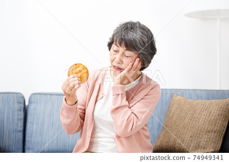 Senior woman eating rice crackers 74949341
