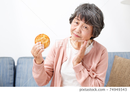 Senior woman eating rice crackers 74949343