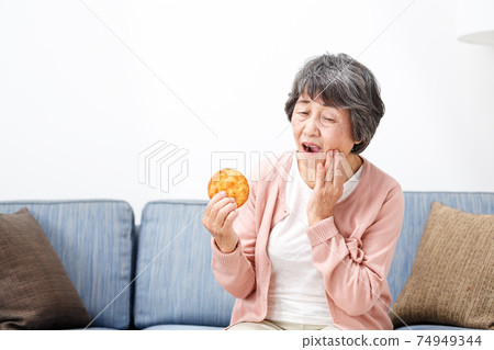 Senior woman eating rice crackers Senior woman eating rice crackers 74949344