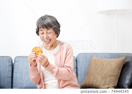 Senior woman eating rice crackers 74949345