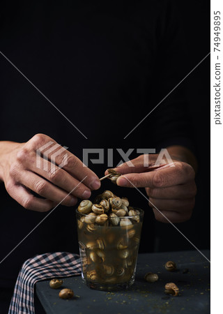 man eating spanish caracolillos, cooked snails man eating spanish caracolillos, cooked snails 74949895
