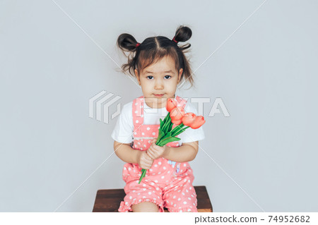 Girl holding a bouquet with tulips in her hands. Children congratulate on the holiday 74952682