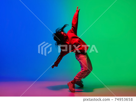 Stylish sportive girl dancing hip-hop in stylish clothes on colorful background at dance hall in neon light. Youth culture, movement, style and fashion, action. Stylish sportive girl dancing hip-hop in stylish clothes on colorful background at dance hall in neon light. Youth culture, movement, style and fashion, action. 74953658