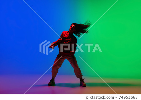 Stylish sportive girl dancing hip-hop in stylish clothes on colorful background at dance hall in neon light. Youth culture, movement, style and fashion, action. 74953665