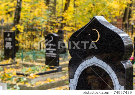 Old islamic cemetery, funeral and burial of muslim. A grave with a stone with crescent moon. Black gravestone Old islamic cemetery, funeral and burial of muslim. A grave with a stone with crescent moon. Black gravestone 74957459