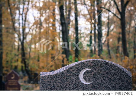 Traditional islamic crescent moon symbol on granite gravestone. Muslim grave in the autumn cemetery Traditional islamic crescent moon symbol on granite gravestone. Muslim grave in the autumn cemetery 74957461