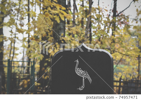 bird painted on tombstone. Muslim grave in an Islamic cemetery. graveyard background bird painted on tombstone. Muslim grave in an Islamic cemetery. graveyard background 74957471